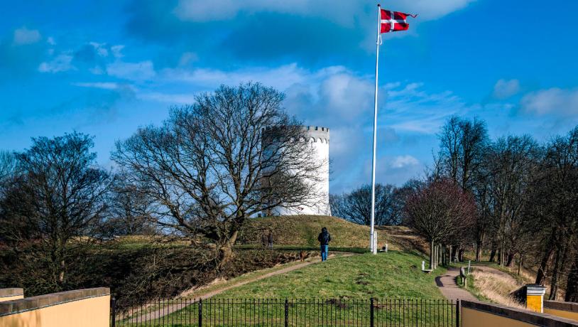 Par på gåtur langs Fredericia Vold i solskin – historisk voldanlæg omgivet af grønne omgivelser.