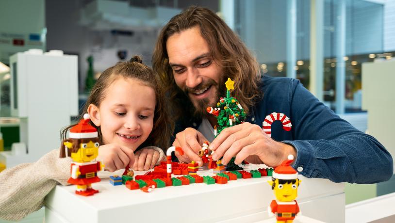 En pige og hendes far bygger på med LEGO®-klodser, mens det er jul