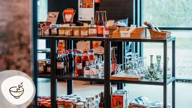 Butik på Museumsgården Karensminde med lokale fødevarer, flasker og glas på hylder, en del af Gastroruten i Small Wonders.