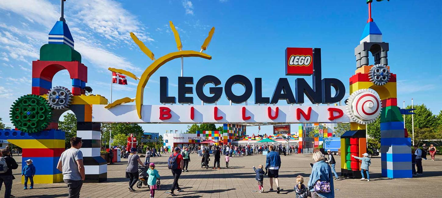 Portalen til LEGOLAND med de to tårne af LEGO® klodser. En masse gæster er på ind for at hygge sig i parken på en sommerdag under en blå himmel.