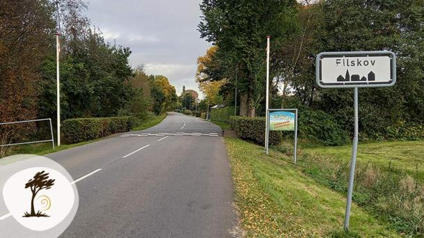Indkørsel til Filskov by med byskilt ved vejen. Filskov er en del af Small Wonders-ruten.