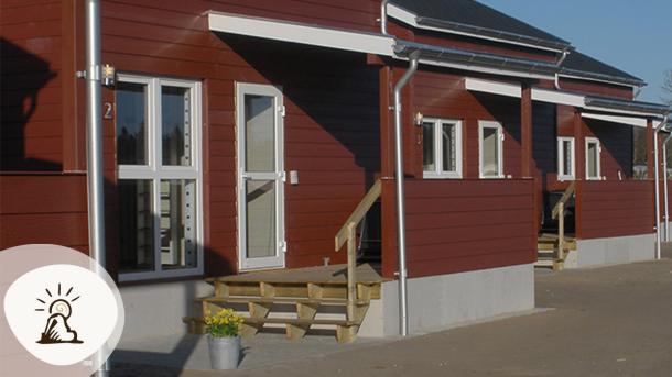 Røde træhytter med små terrasser på Vorbasse Camping, et af overnatningsstederne på Kunstruten i Small Wonders – Heart of Jutland.