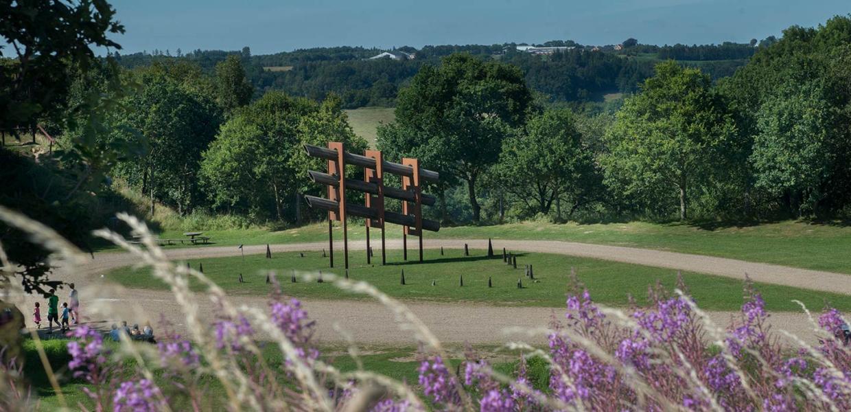 kulptur af Robert Jacobsen i Tørskind Grusgrav, omgivet af grønne bakker, træer og vilde blomster. Grusgraven er et stop på Kunstruten i Small Wonders – Heart of Jutland.