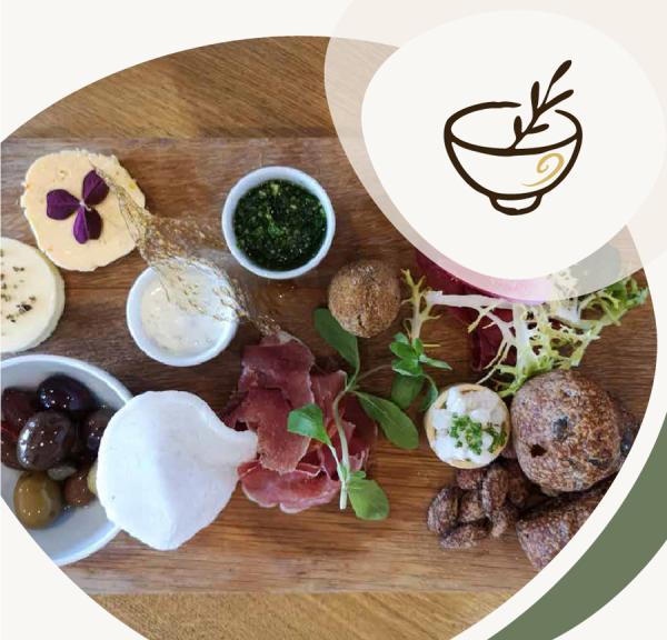 Anrettet tapasbræt med ost, kød, oliven, brød, grønt og små dip, illustreret med et ikon af en skål øverst til højre.