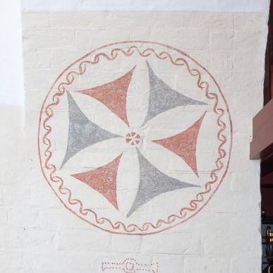 To kalkmalerier på væggen i Vorbasse Kirke, med geometriske mønstre i røde og grå nuancer. Kirken er et stop på Kunstruten i Small Wonders – Heart of Jutland.