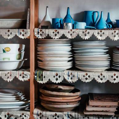 Interiør fra køkkenet på Museumsgården Karenminden. Der står tallerkener, skåle og kander på åbne hylder.