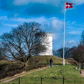 Par på gåtur langs Fredericia Vold i solskin – historisk voldanlæg omgivet af grønne omgivelser.