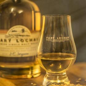 Whisky fra destilleriet Fary Lochan i et glas med en flaske bagved.