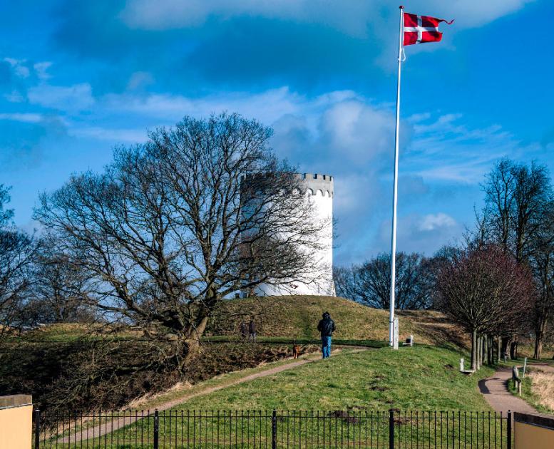 Par på gåtur langs Fredericia Vold i solskin – historisk voldanlæg omgivet af grønne omgivelser.