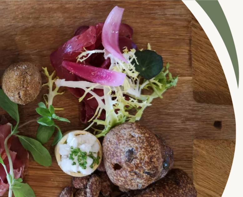 Anretning med brød, charcuteri, grønt og syltede løg på træbræt. Topbillede til Gastroruten i Small Wonders – Heart of Jutland.